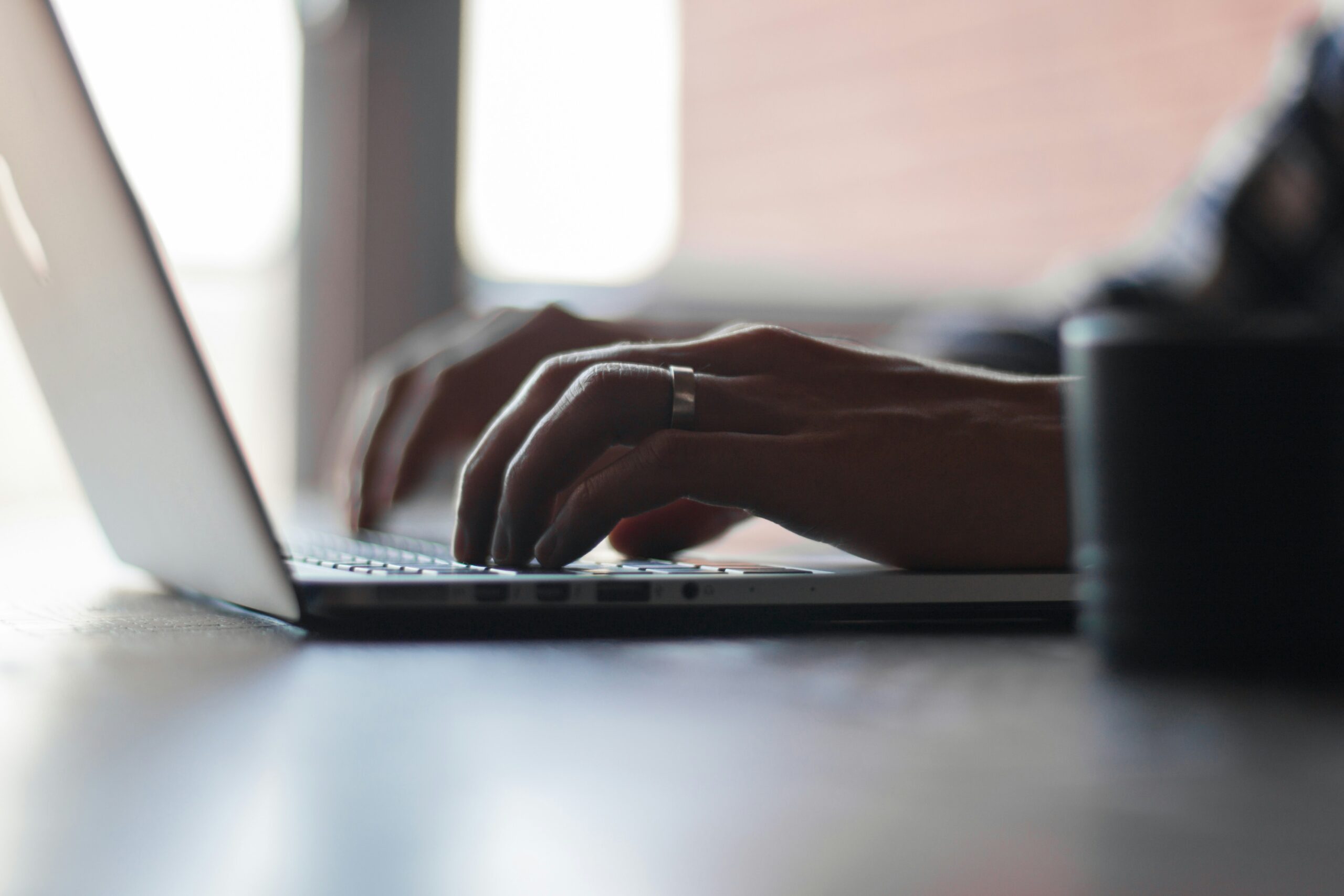 A person typing on a laptop in a well-lit room, with their hands focused on the keyboard, symbolizes content creation and SEO optimization for featured snippets.